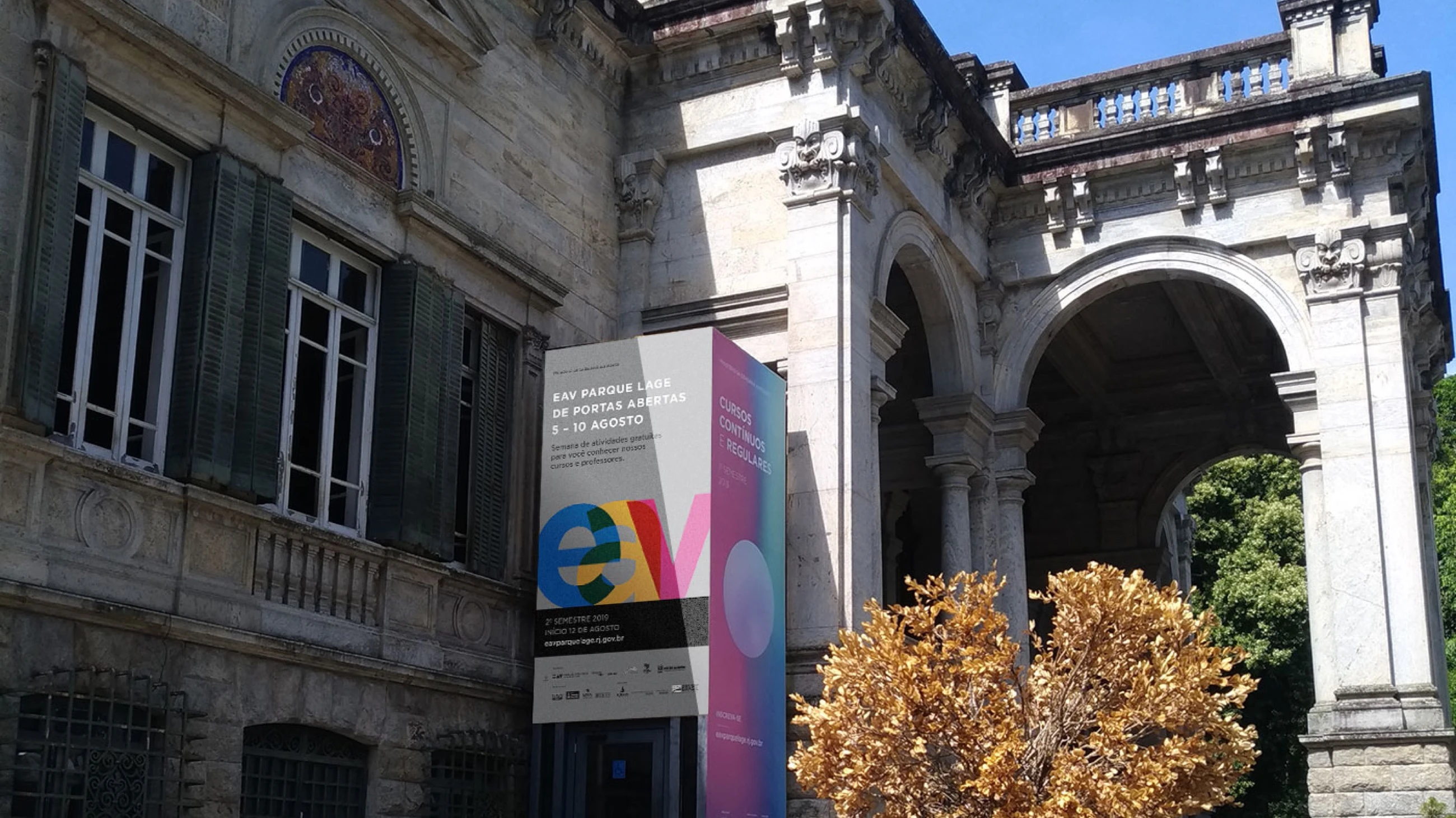 Fachada do Palacete do Parque Lage com o banner colorido da campanha de cursos.